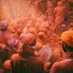 Vibrant Holi celebration with people covered in colors in Barsana, India.